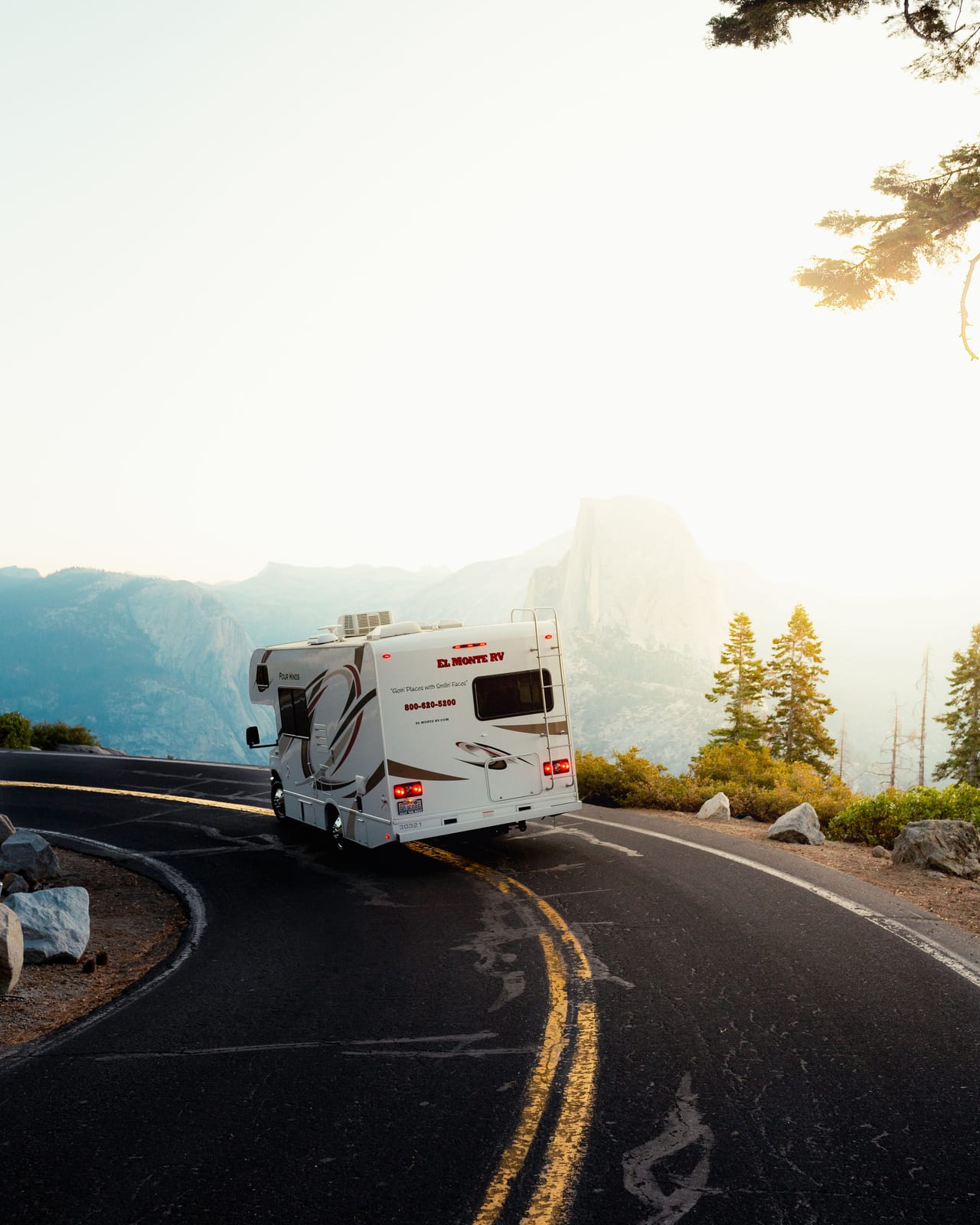 Motorhome following a winding mountain road with forested peaks in the background.